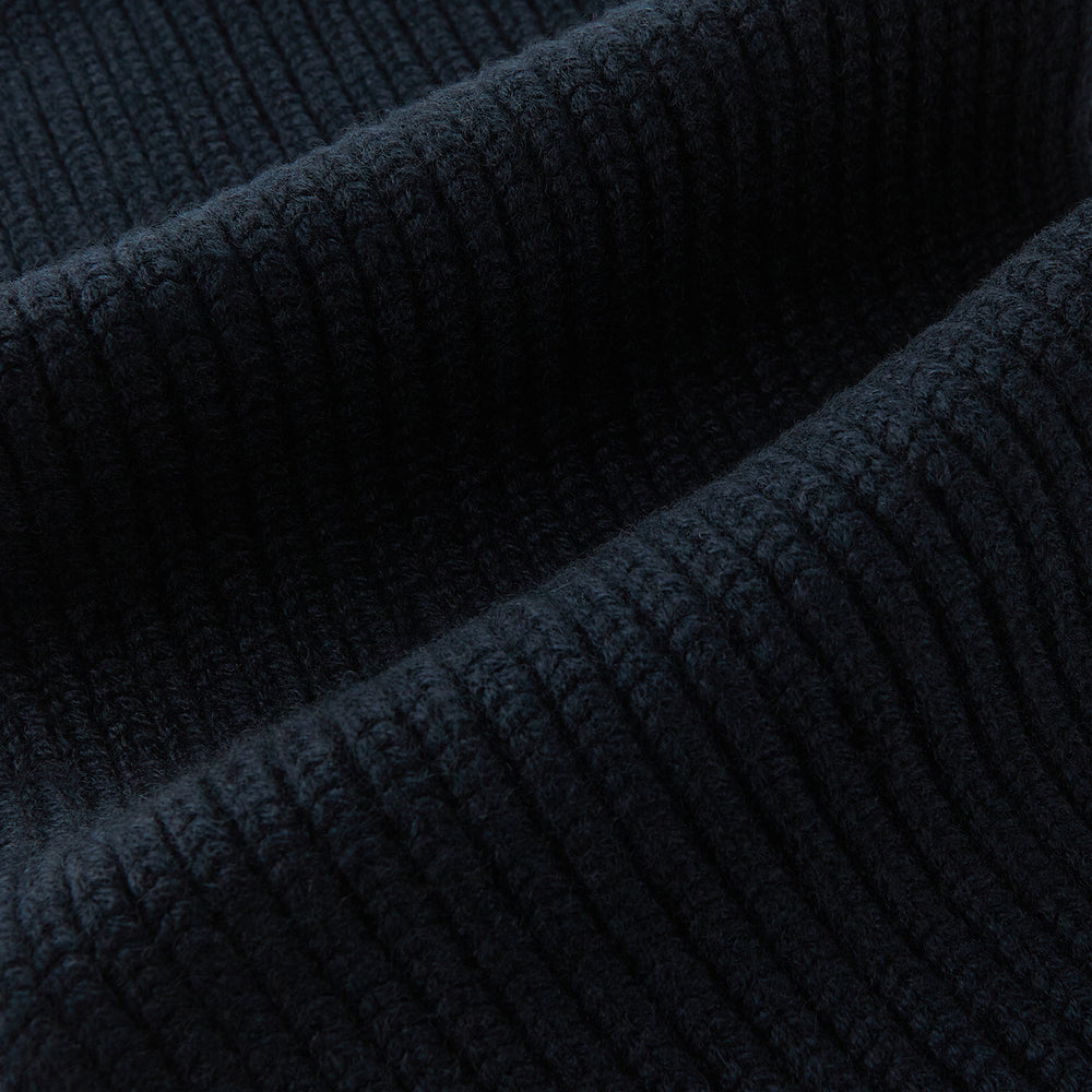 The Navy Rib-Knit Cashmere Scarf by Turnbull & Asser is neatly folded and looped in a simple knot against a white background, highlighting its refined luxury appeal.