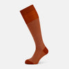 View 1 of product The Turnbull & Asser SOCKS LONG COTTON HOUNDSTOOTH ROSE is a single over-the-calf sock in rusty orange with a white houndstooth pattern and solid orange toe, heel, and cuff, shown on a plain white background.