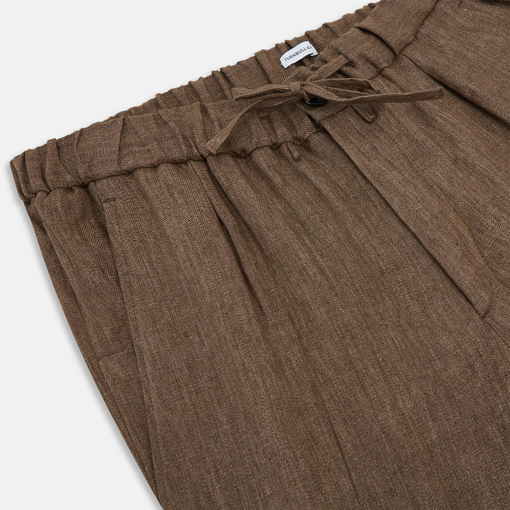 The Turnbull & Asser Pine Cone Linen Herringbone Miles Trousers feature a relaxed fit, elasticated waistband, and drawstring tie, shown against a plain white background.
