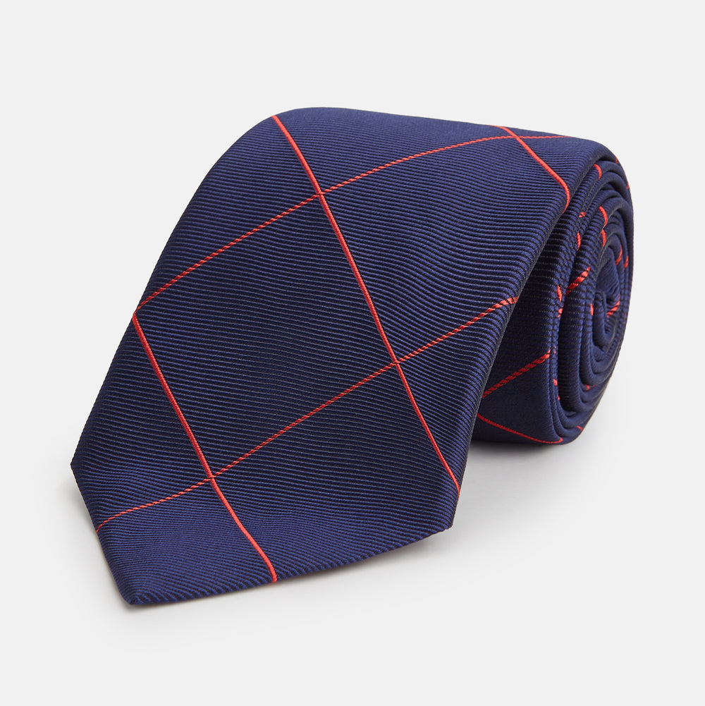 The Turnbull & Asser Red and Navy Window Pane Silk Tie features a refined diagonal red pattern on navy silk, making it an elegant choice for office attire.