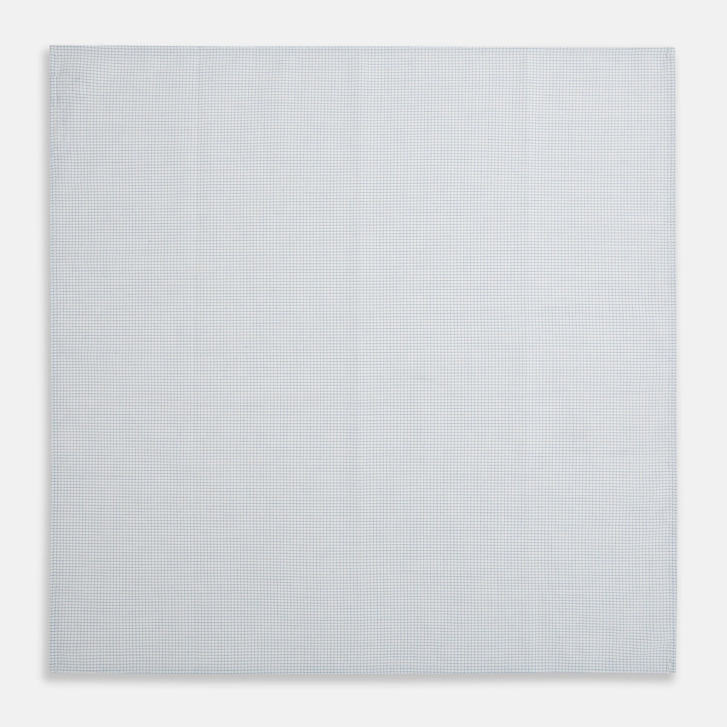 View 2 of product The Turnbull & Asser Hand Rolled Pale Blue Graph Check Handkerchief features a neatly folded white cotton design with a pale blue check, offering an elegant finishing touch to any setting.