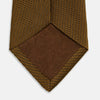 View 4 of product The Turnbull & Asser Plain Lace Jacquard Earth Tie, an essential brown wardrobe accessory, is shown rolled up against a plain white background.