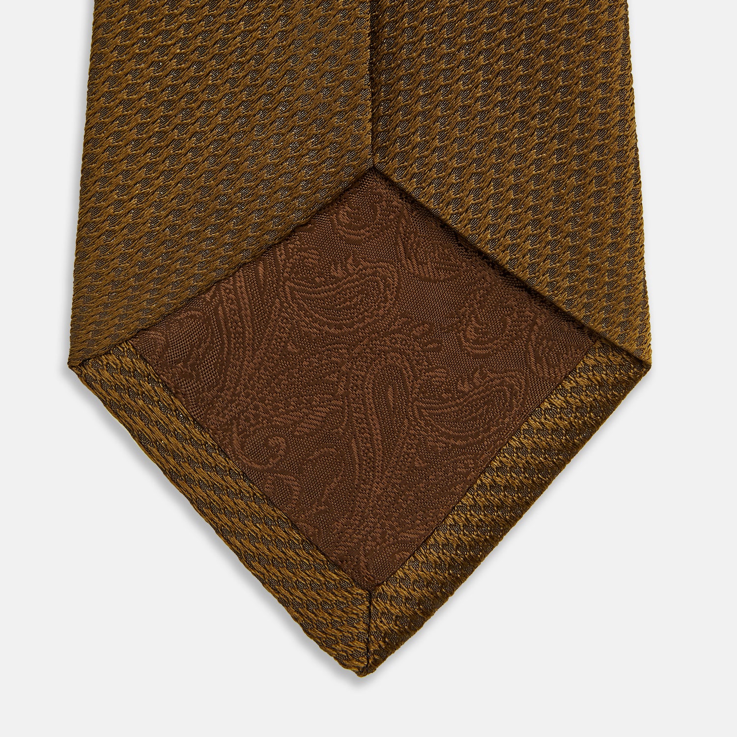 View 4 of product The Turnbull & Asser Plain Lace Jacquard Earth Tie, an essential brown wardrobe accessory, is shown rolled up against a plain white background.