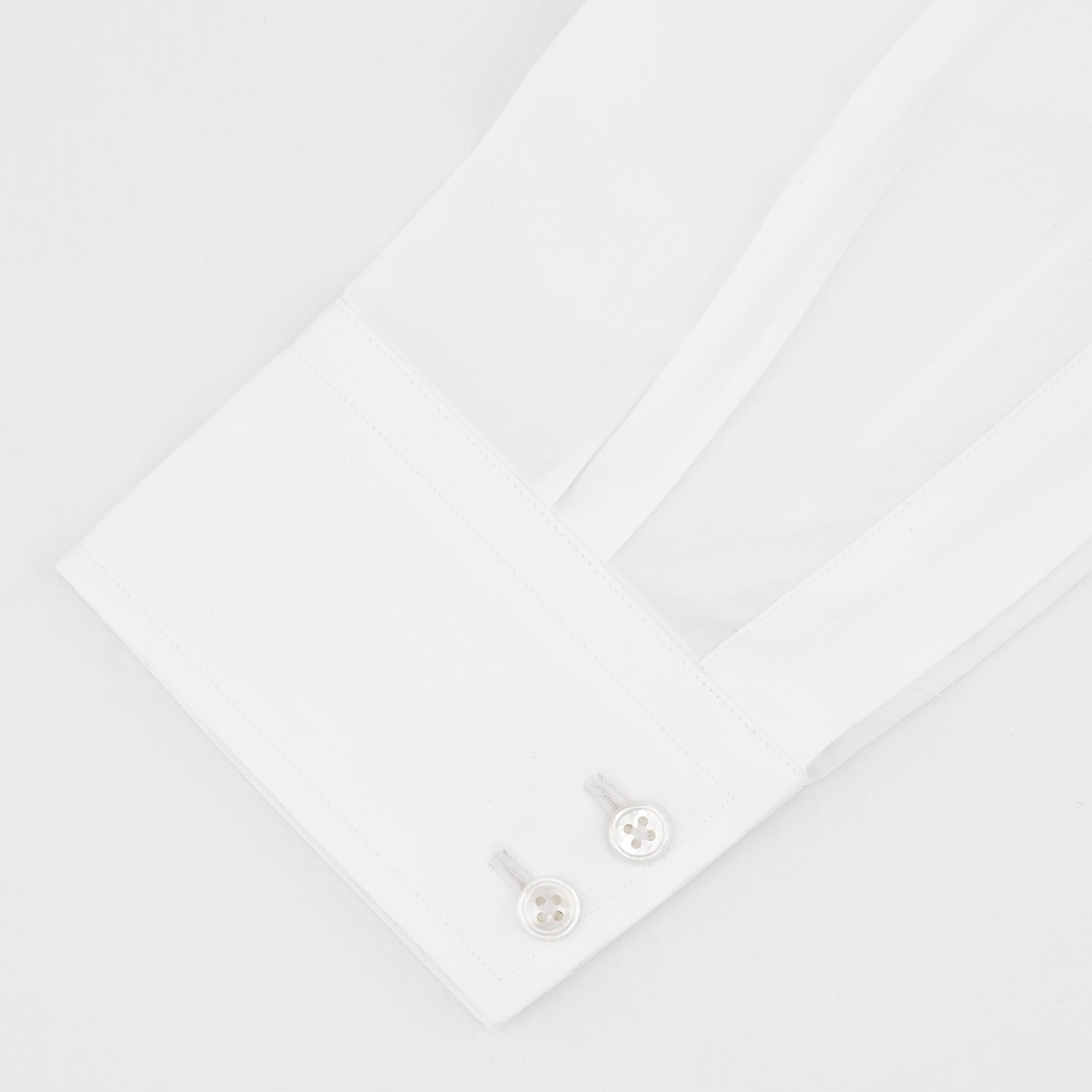 View 2 of product A Turnbull & Asser Tailored Fit Two-Fold 120 White Cotton Shirt with a Kent collar and 2-button cuffs is neatly folded against a light blue background, displaying the brand label inside the collar.