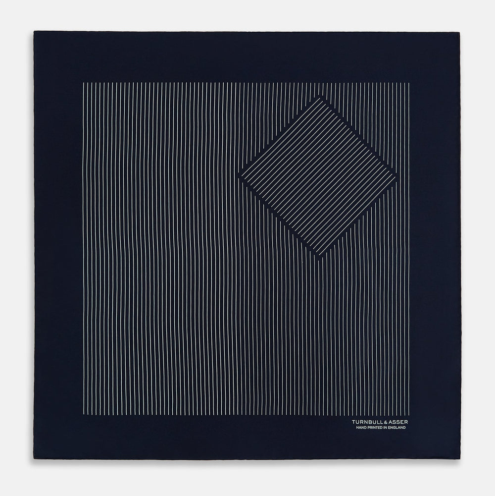 The Navy and White Stripe Silk Pocket Square by Turnbull & Asser features thin white vertical stripes and "TURNBULL & ASSER HAND PRINTED IN ENGLAND" in one corner, with a folded edge showing the reverse of this elegant silk accessory.