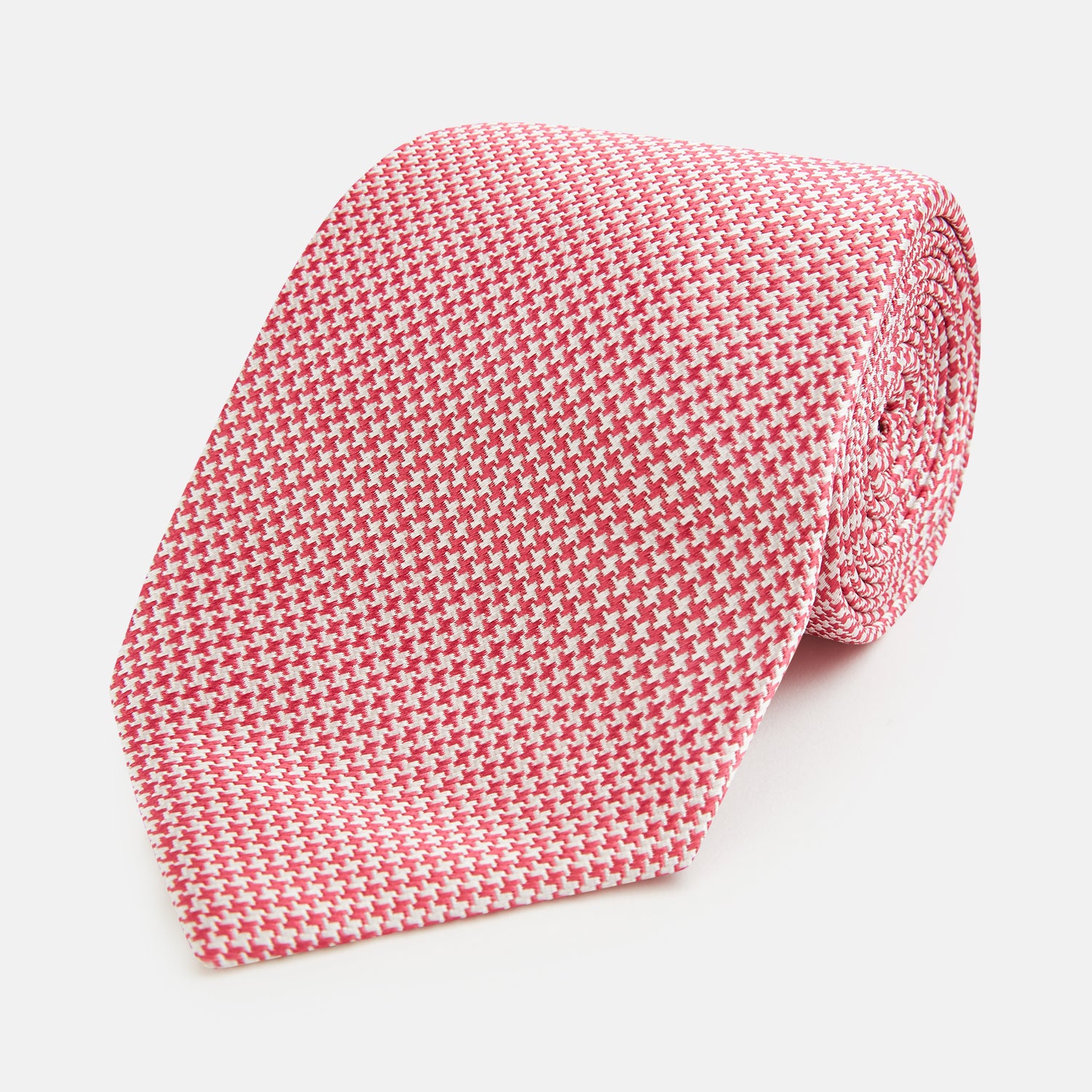 View 1 of product The Turnbull & Asser Pink and White Houndstooth Silk Tie features a small pattern and is displayed rolled up on a plain white background, making it perfect for pairing with any office shirt.