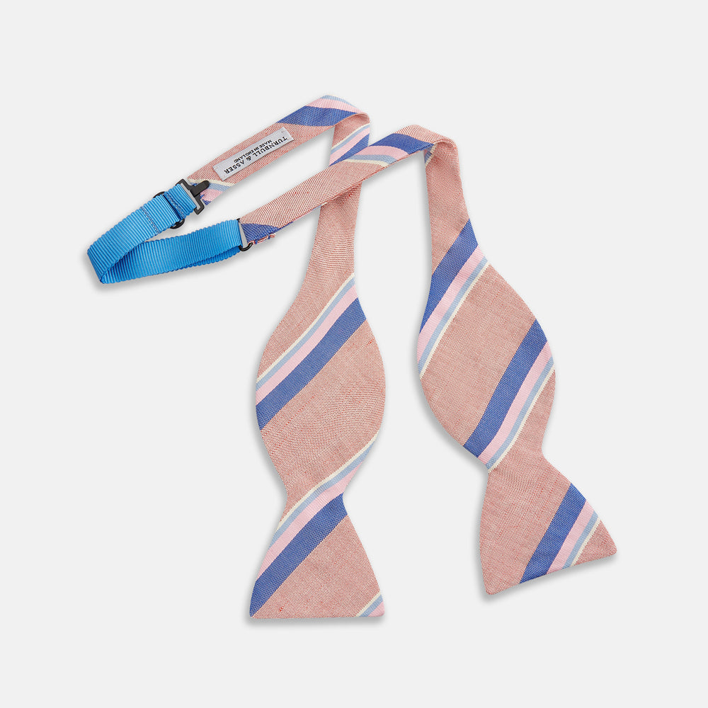 The Thistle-Petersham-Double End Bow Tie by Turnbull & Asser features a pink base with diagonal blue, white, and navy stripes—a versatile accessory perfect for any gentleman's wardrobe.