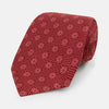 View 1 of product The Turnbull & Asser Red Medallion Silk Tie features a repeating white geometric medallion motif on vibrant red silk, shown against a plain white background.