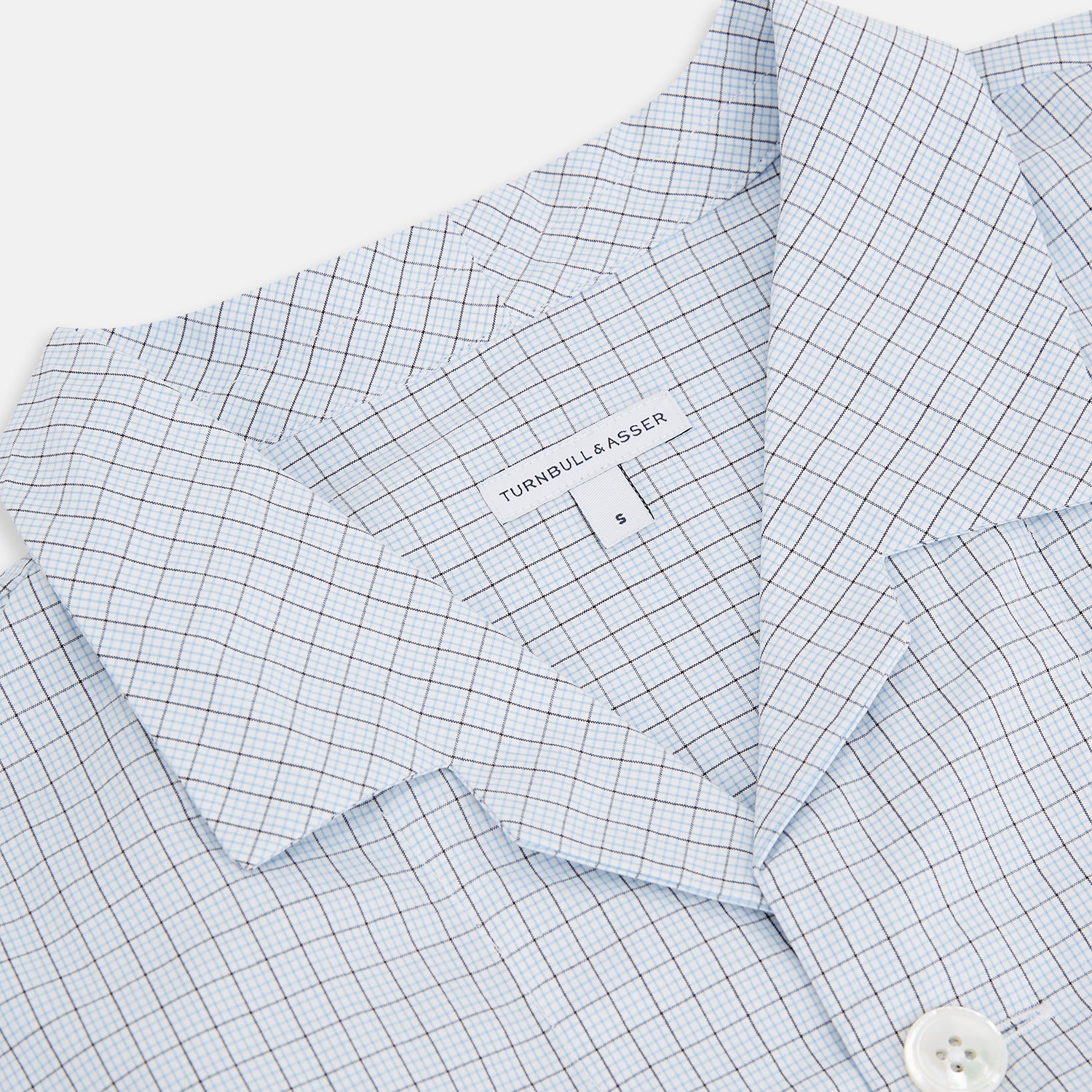 View 2 of product The Turnbull & Asser Blue Graph Check Pyjama Shirt features long sleeves, a collar, and a small check pattern in light blue—ideal as elegant loungewear.