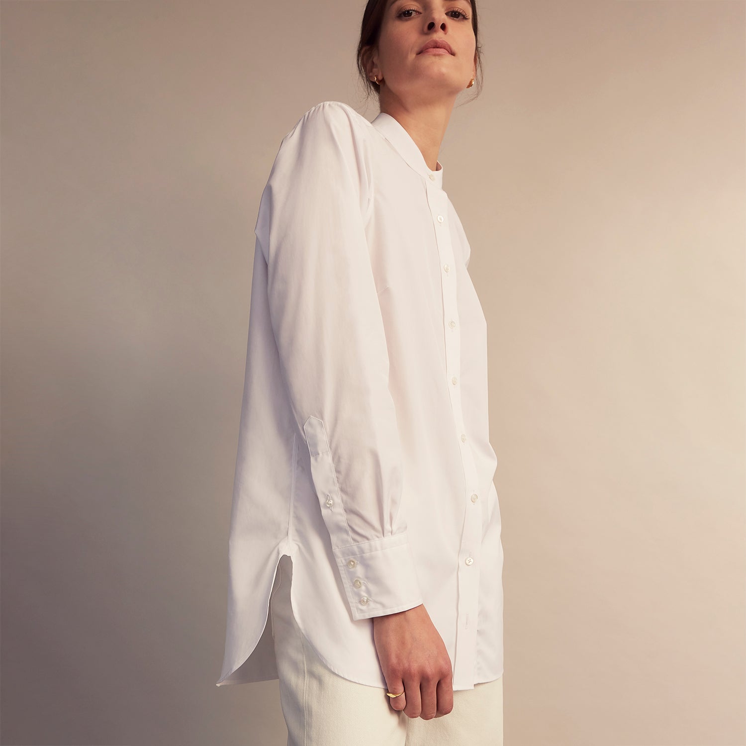View 6 of product The White Cotton Lauren Shirt by Turnbull & Asser, featuring a stand collar, button-down front, and elongated body, is laid flat on a plain white background.
