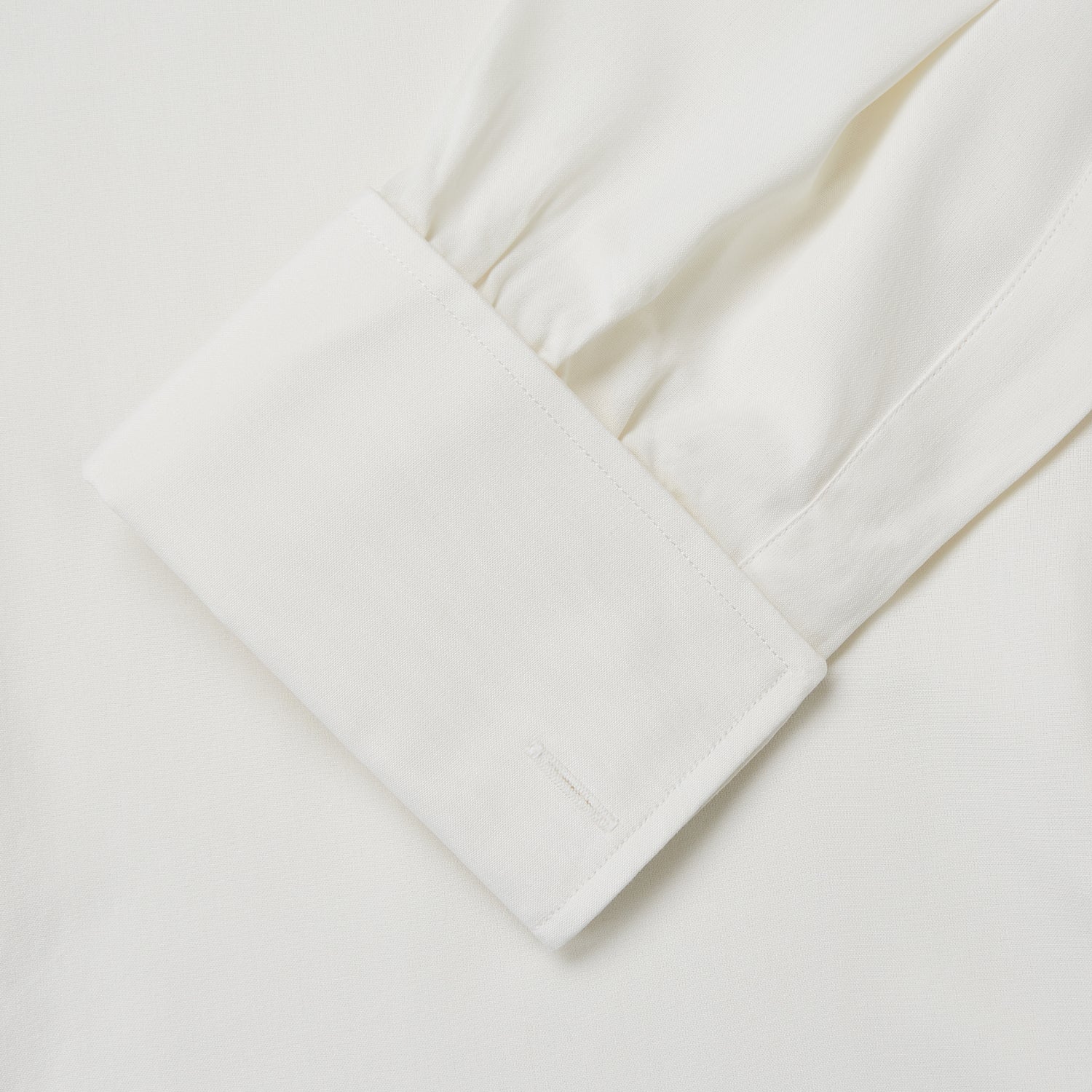 View 4 of product The Turnbull & Asser Cream Silk Tailored Fit Shirt is a long-sleeve button-up with a pointed collar and buttoned cuffs, displayed laid flat against a plain white background.