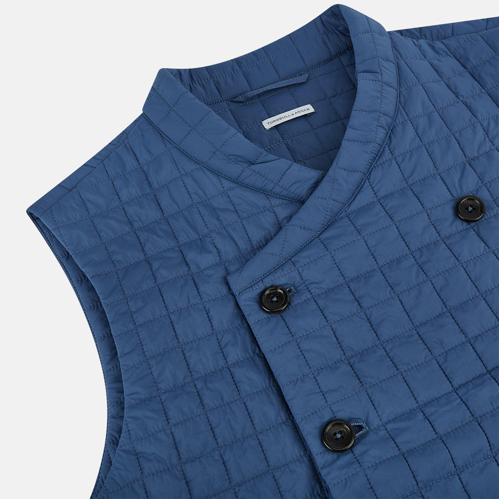 The Azzurro Double-Breasted Quilted Gilet by Turnbull & Asser is a sleeveless blue piece with black buttons, two zippered pockets, and a chest pocket—ideal for layered looks against a plain white background.