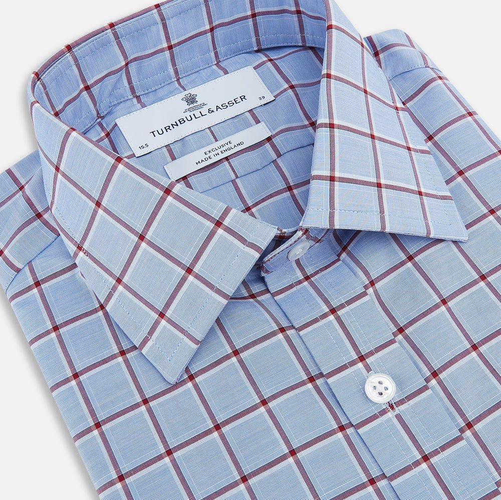 The Turnbull & Asser Blue and Burgundy Windowpane Mayfair Shirt features long sleeves, a light blue base with burgundy windowpane checks, a classic collar, and white buttons.