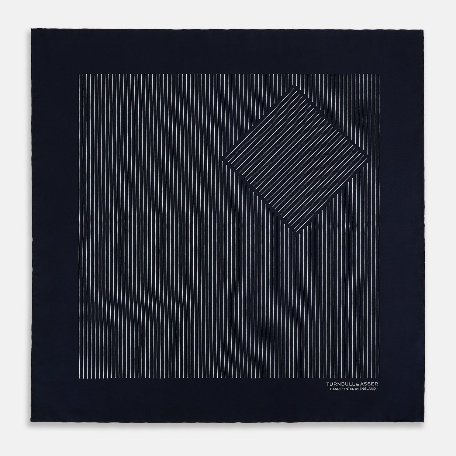 View 4 of product A Navy and Grey Stripe Silk Pocket Square by Turnbull & Asser, featuring hand-rolled edges and brand text in the corner. One corner is folded to show the reverse side.