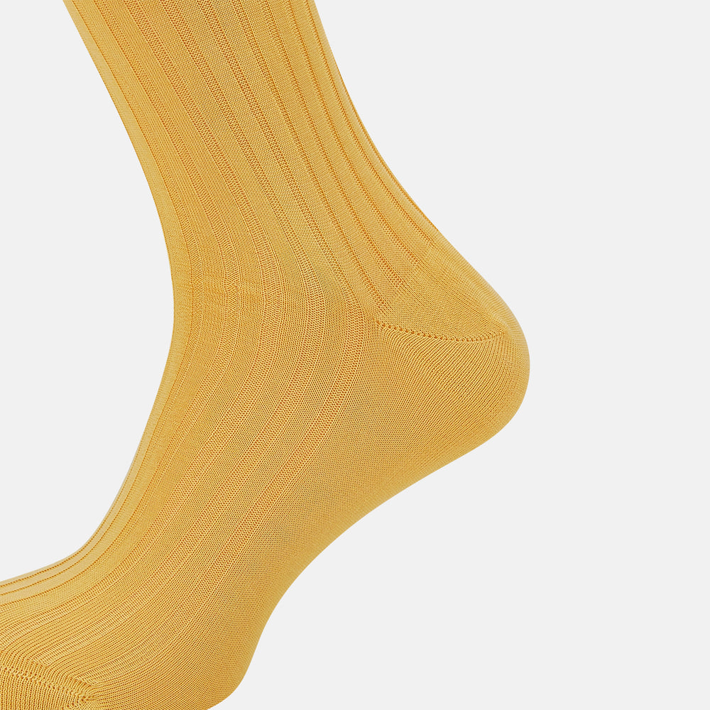 The Turnbull & Asser Banana Long Socks are knee-high, golden-yellow, and made from mercerised Egyptian cotton, shown upright on a white background to highlight their ribbed texture and fitted shape.