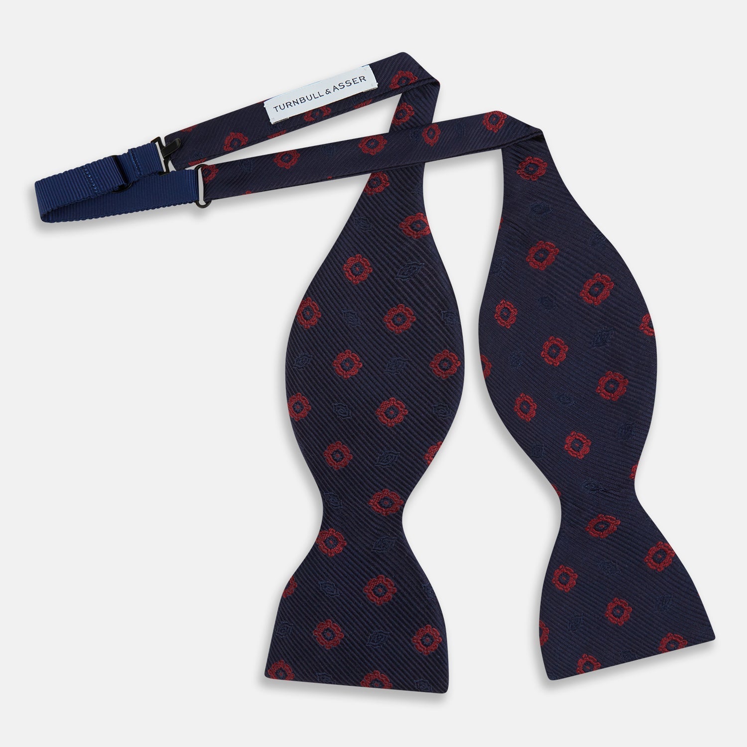 View 2 of product Elevate your formalwear with the Turnbull & Asser Navy and Burgundy Motif Silk Bow Tie, featuring a subtle ribbed texture and repeating red geometric motifs.