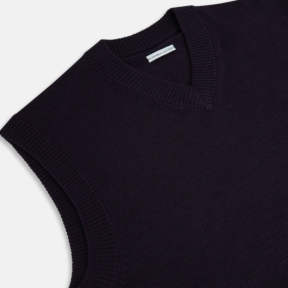 The Turnbull & Asser Dark Purple Fine Merino V-Neck Vest features ribbed edges and a sleeveless design, ideal for a gentleman’s style in cooler seasons, and is displayed on a plain white background.