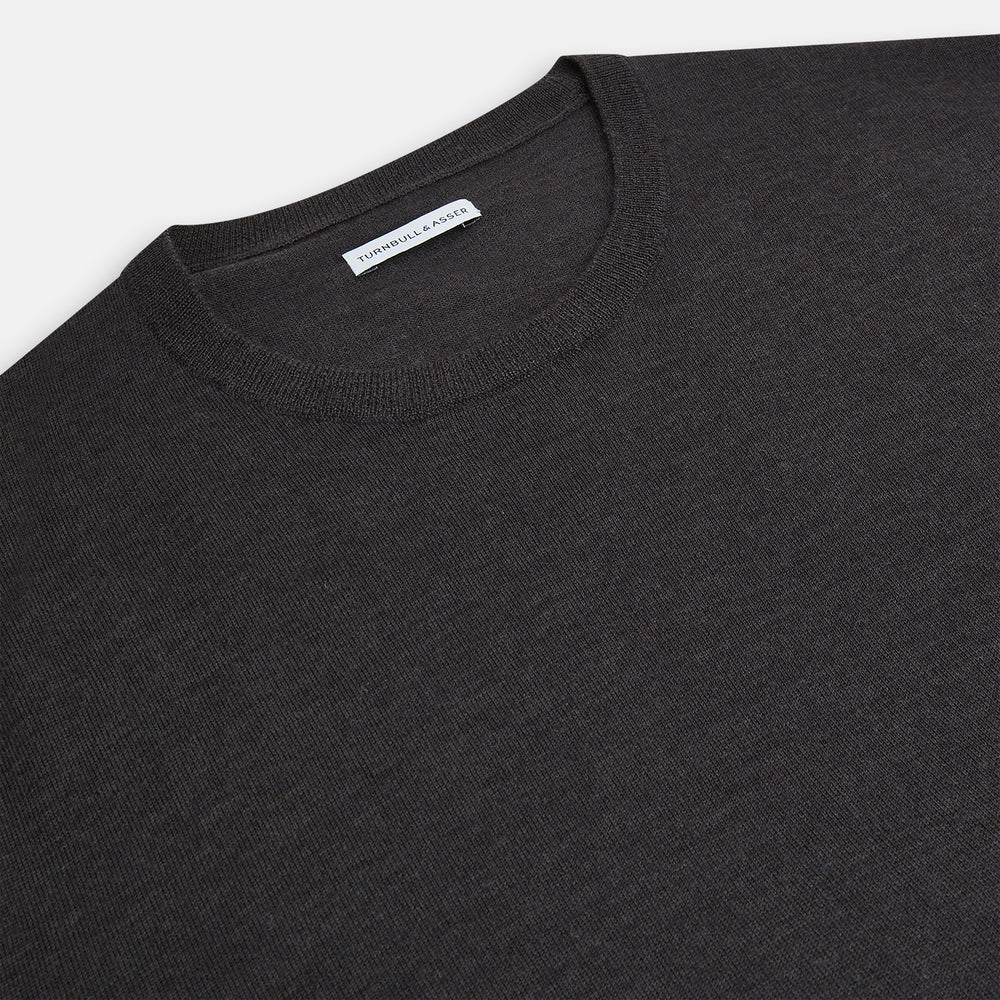 The Turnbull & Asser Charcoal Grey Fine Merino Round Neck Jumper for men features long sleeves, ribbed cuffs, hem, and collar. Displayed on a white background, this classic knitwear piece has a plain design with no visible logos or patterns.