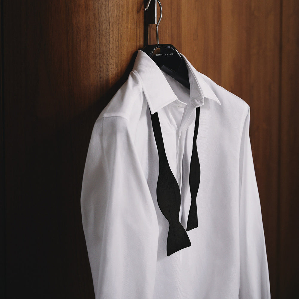 The Casino Royale Bow Tie by Turnbull & Asser, as seen on James Bond, is a classic black Shantung silk bow tie with a smooth, slightly shiny finish, shown against a plain white background.
