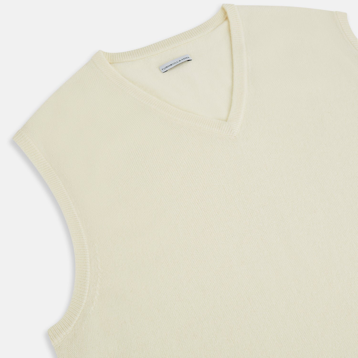 View 2 of product The Turnbull & Asser White Cashmere V-neck Vest is a sleeveless ivory knit with ribbed trim, ideal for layering in cooler weather, shown against a plain white background.