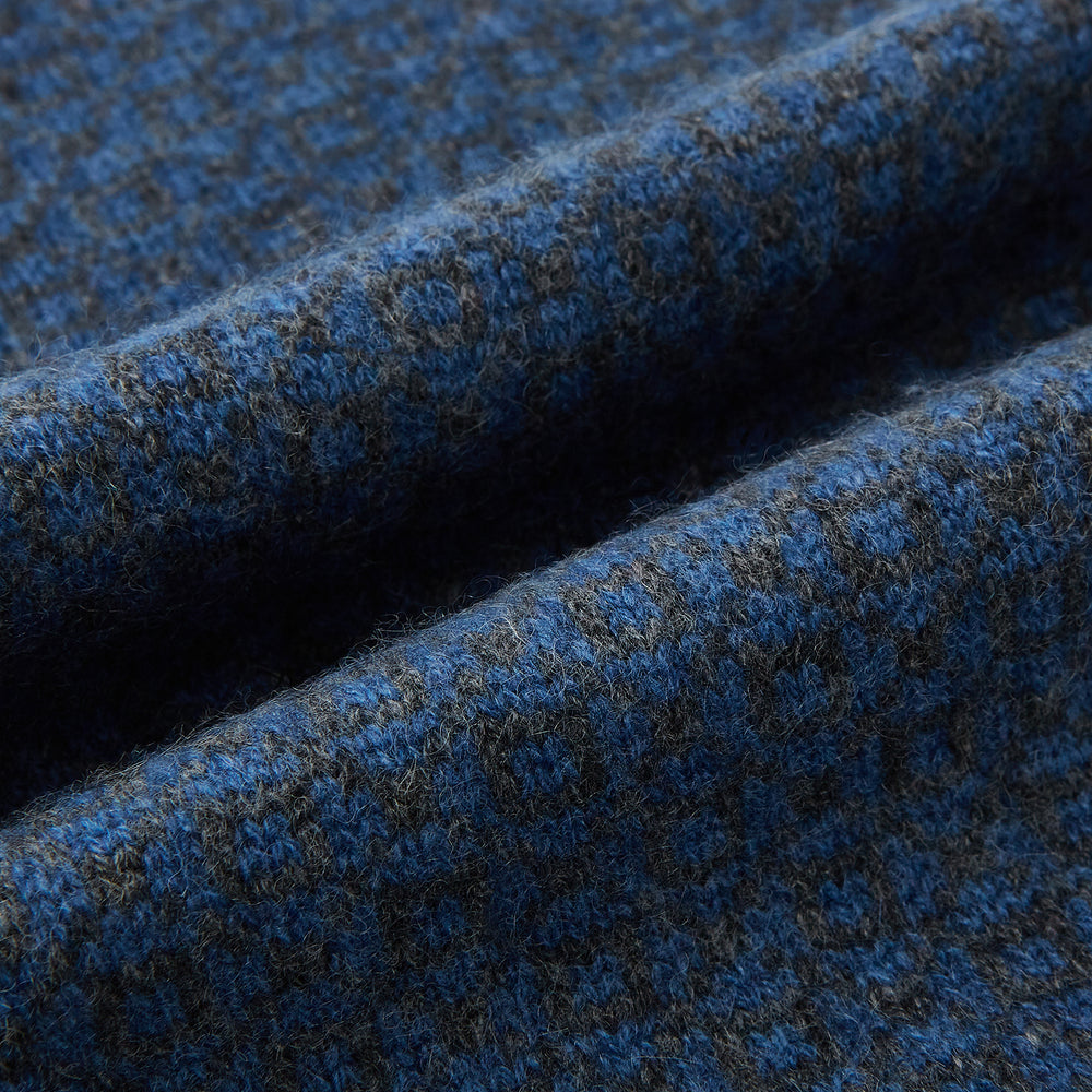 The Azzurro and Graphite Lozenge-Patterned Cashmere Knitted Scarf by Turnbull & Asser features a blue geometric design and luxurious softness, displayed in a looped drape with both ends hanging against a white background.