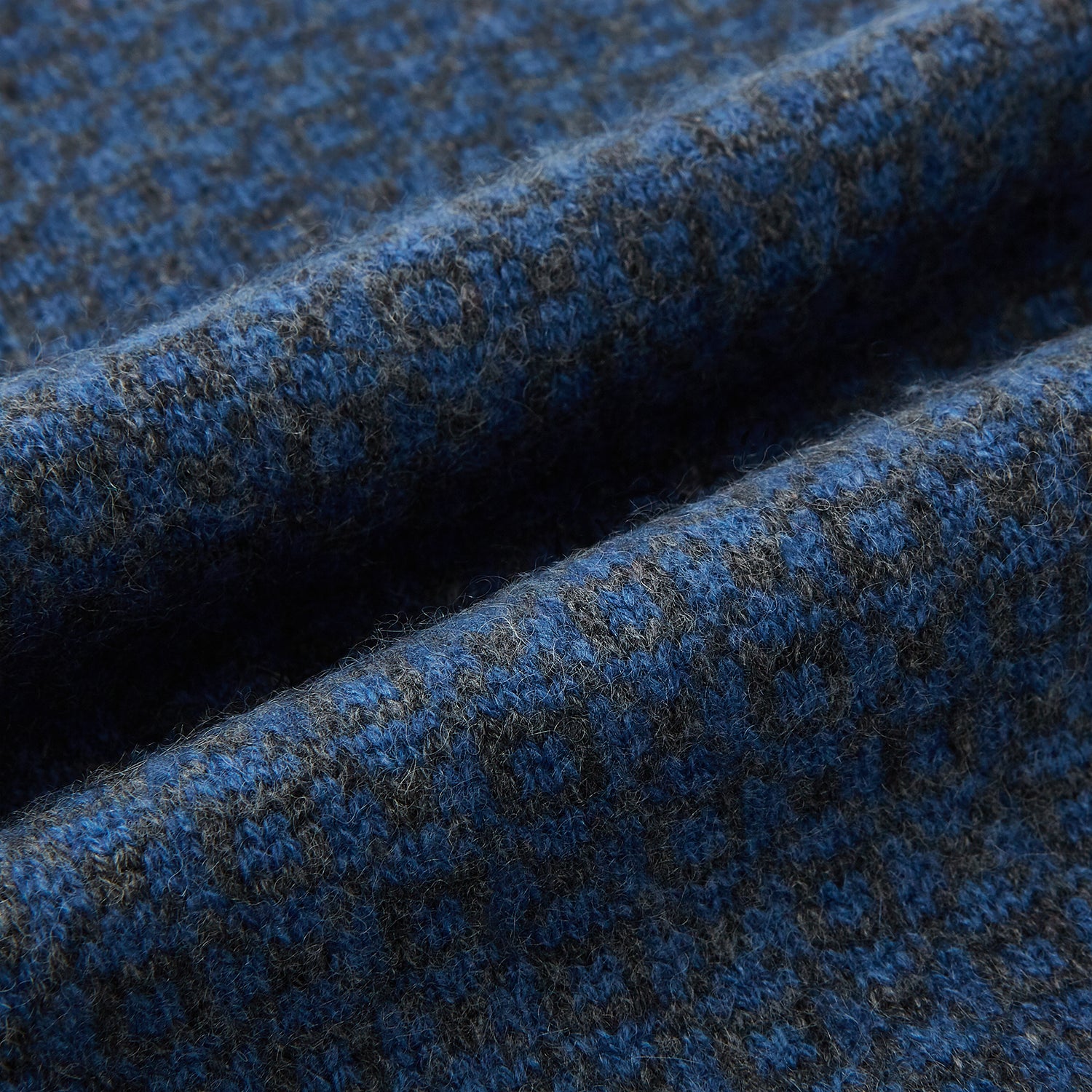 View 3 of product The Azzurro and Graphite Lozenge-Patterned Cashmere Knitted Scarf by Turnbull & Asser features a blue geometric design and luxurious softness, displayed in a looped drape with both ends hanging against a white background.