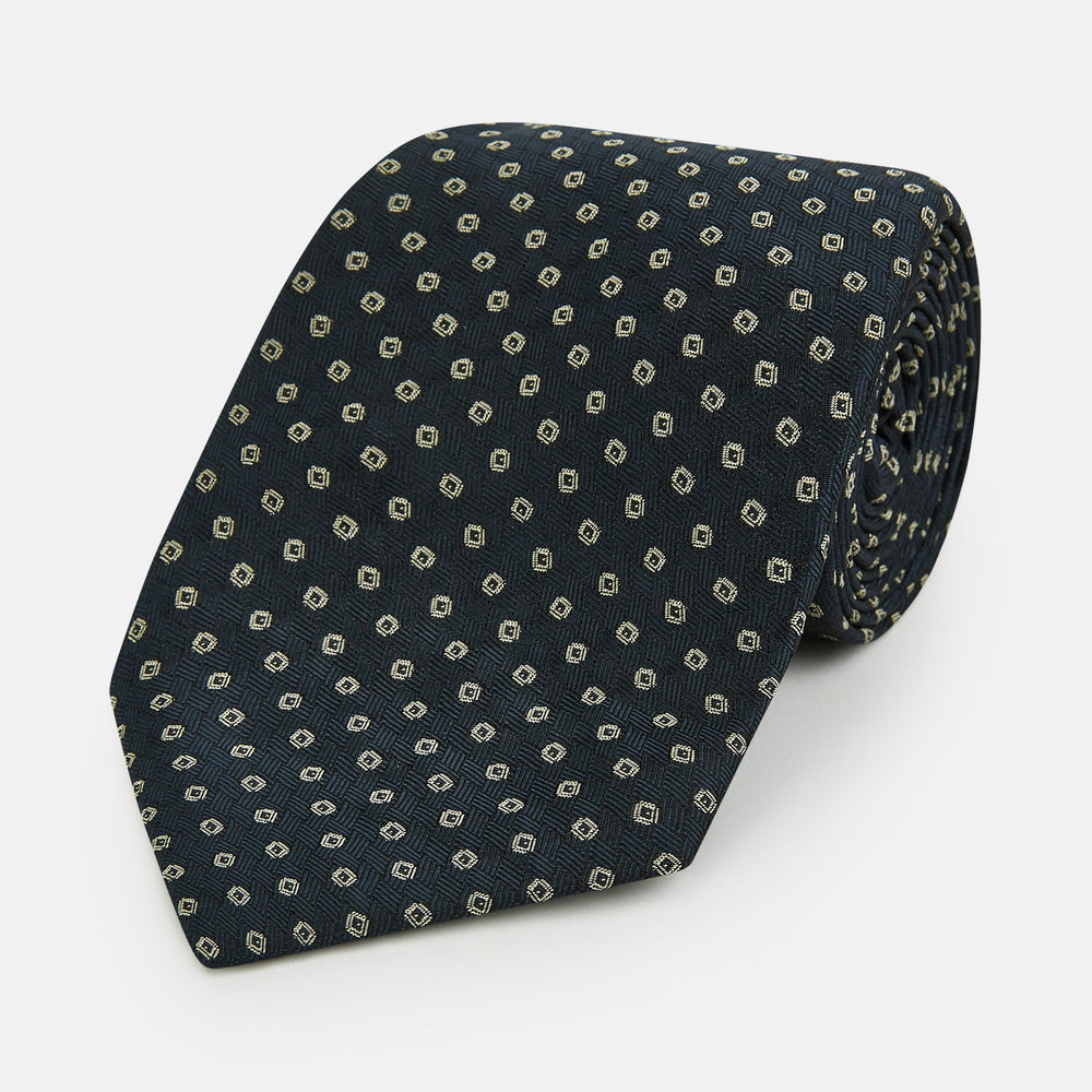 The Turnbull & Asser Navy and White Circle Silk Tie features a repeating circle pattern and is shown rolled on a white background—a timeless men's accessory for any occasion.