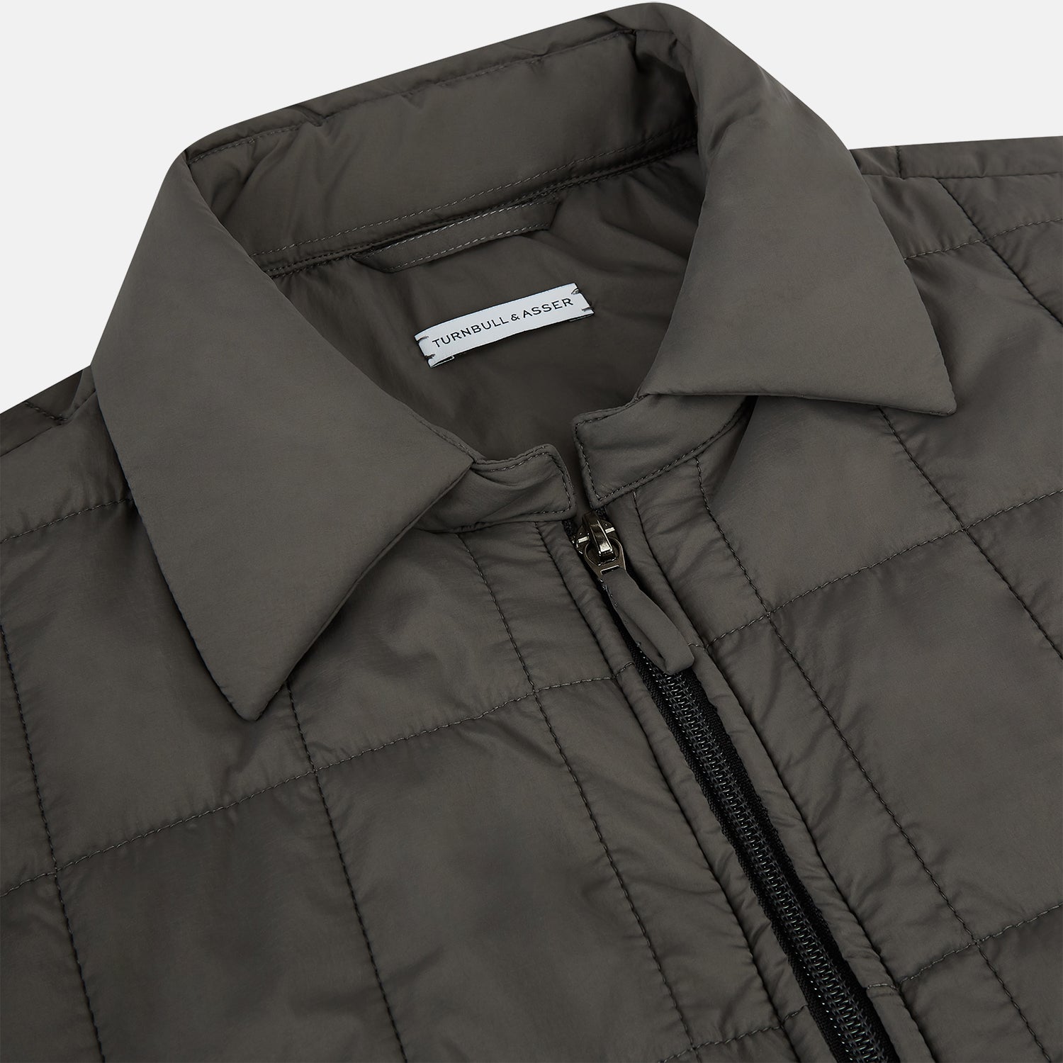 View 2 of product The Battersea Shadow Grey Quilted Jacket by Turnbull & Asser features a front zipper, buttoned cuffs, pointed collar, and multiple pockets—an ideal choice for the modern gentleman. Shown on a plain white background.