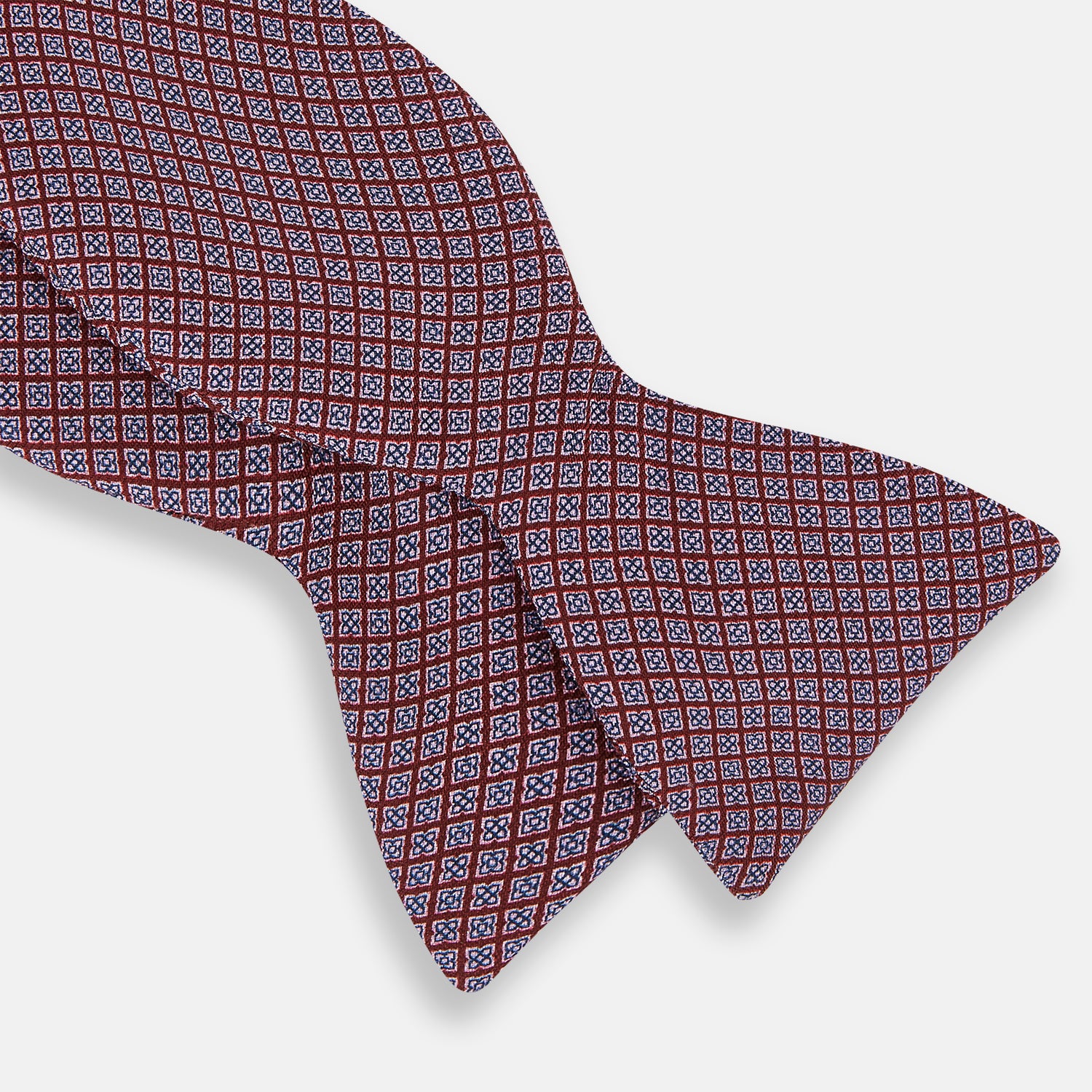 View 2 of product The Indies Red Floral Square-Print Silk Bow Tie by Turnbull & Asser features a geometric blue and white diamond pattern on red silk, styled against a white background for classic British elegance.
