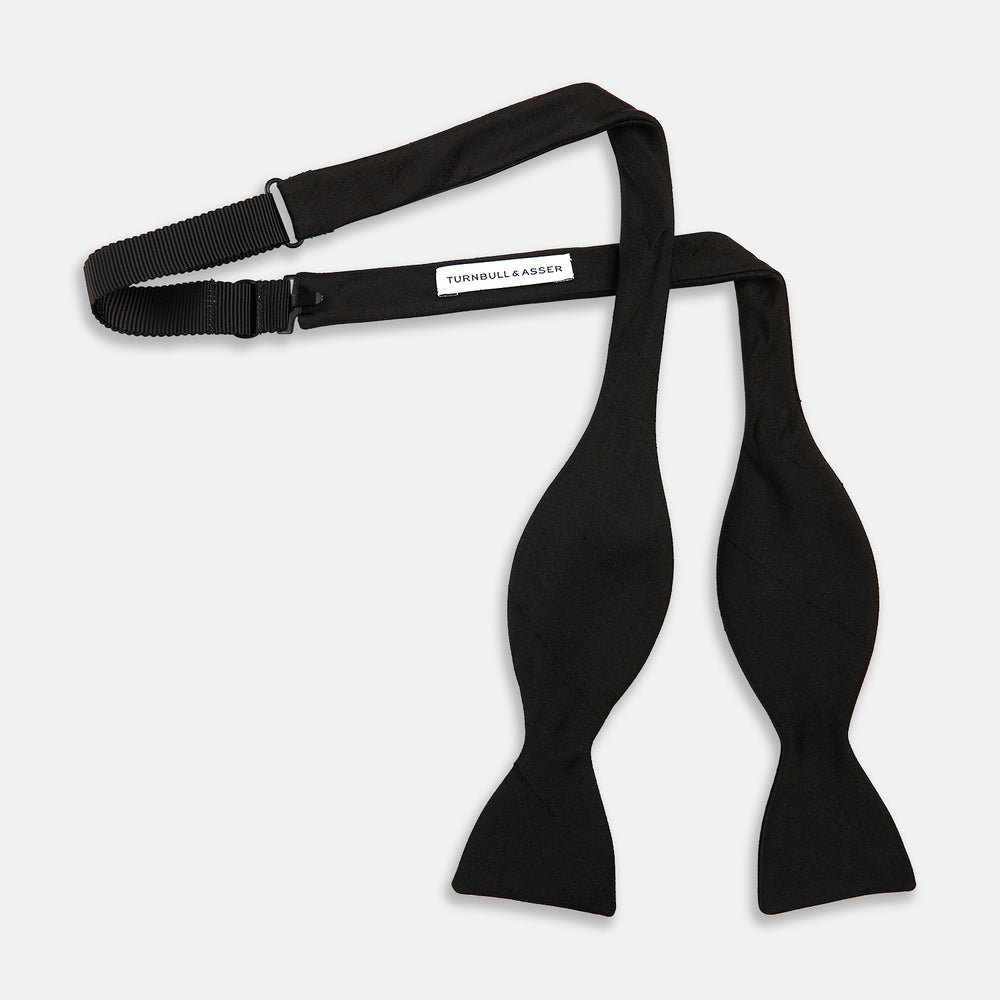 The Casino Royale Bow Tie by Turnbull & Asser, as seen on James Bond, is a classic black Shantung silk bow tie with a smooth, slightly shiny finish, shown against a plain white background.