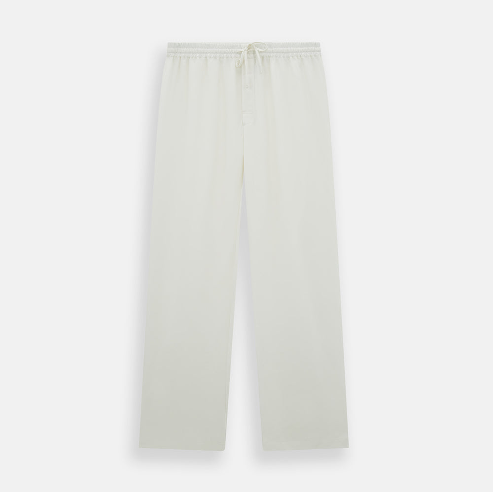 The Turnbull & Asser Cream Silk Pyjama Set, shown laid flat on a white background, features a long-sleeve button-up top with a chest pocket and matching pants with an elastic drawstring waist—ideal for comfortable loungewear.