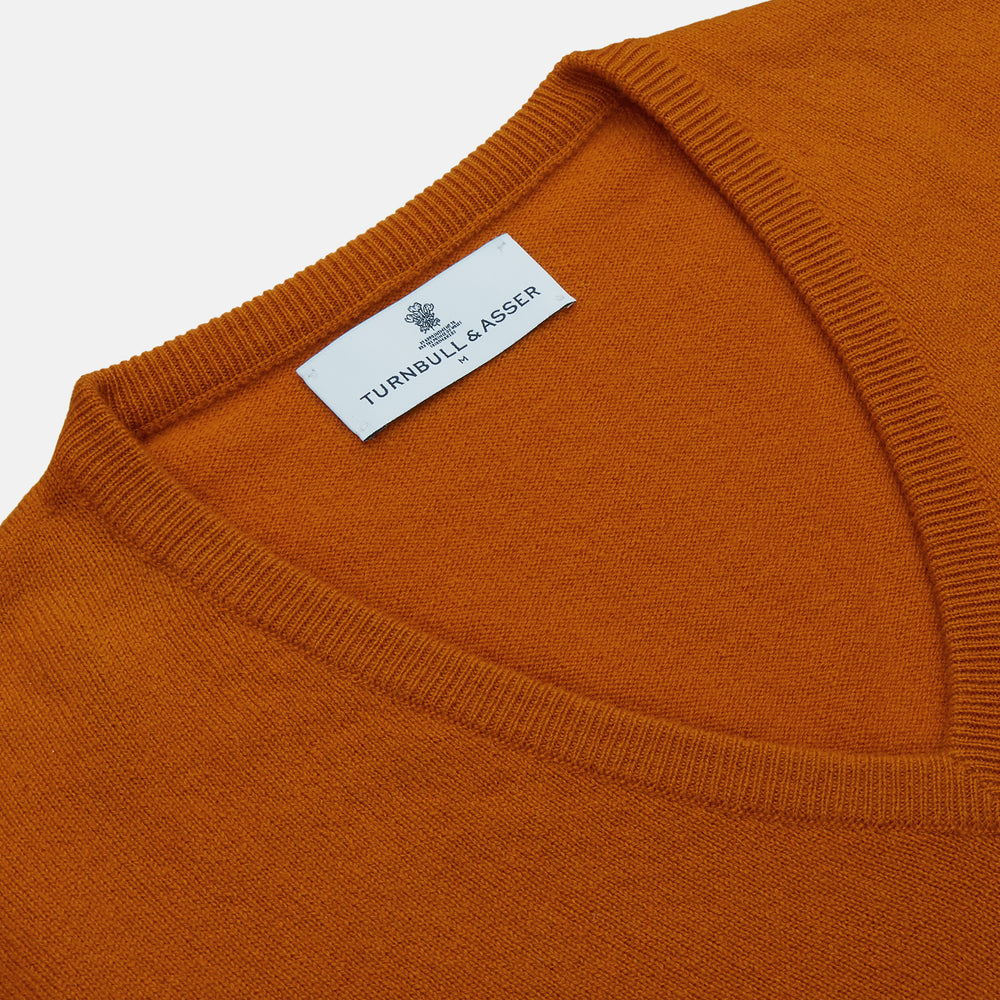 The Rust Ifor Slipover by Turnbull & Asser, a sleeveless V-neck in burnt orange, is made from lightweight Scottish cashmere and displayed flat on a white background.