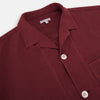 View 2 of product The Turnbull & Asser Burgundy Silk Pyjama Set features a long-sleeve, button-up shirt with chest pocket and matching pants with elastic waistband and side pocket, shown on a white background.