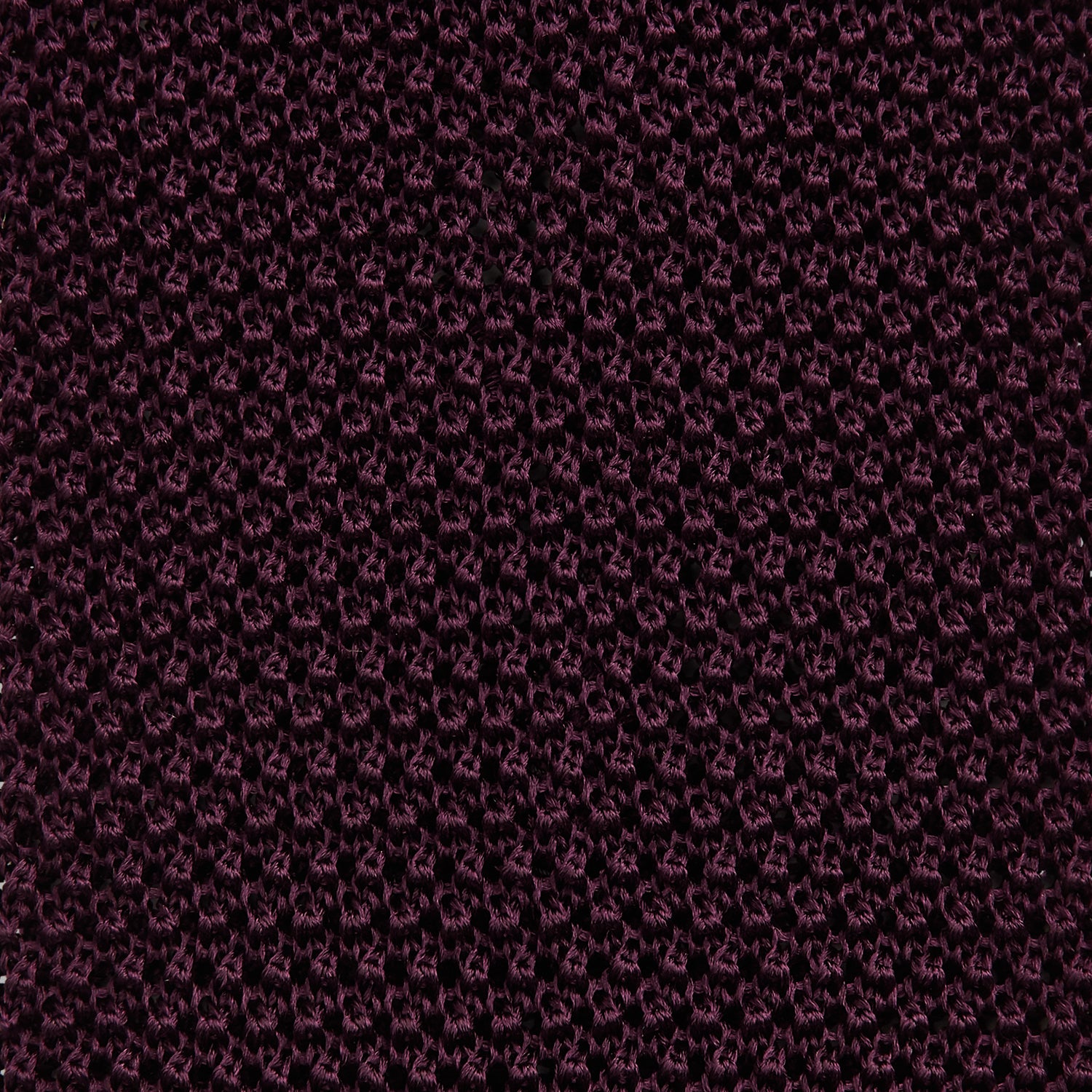 View 3 of product The Turnbull & Asser Knitted Burgundy Square Silk Plain Tie, featuring a textured open-weave pattern, is rolled up and displayed on a plain white background—a versatile accessory for the modern gentleman.