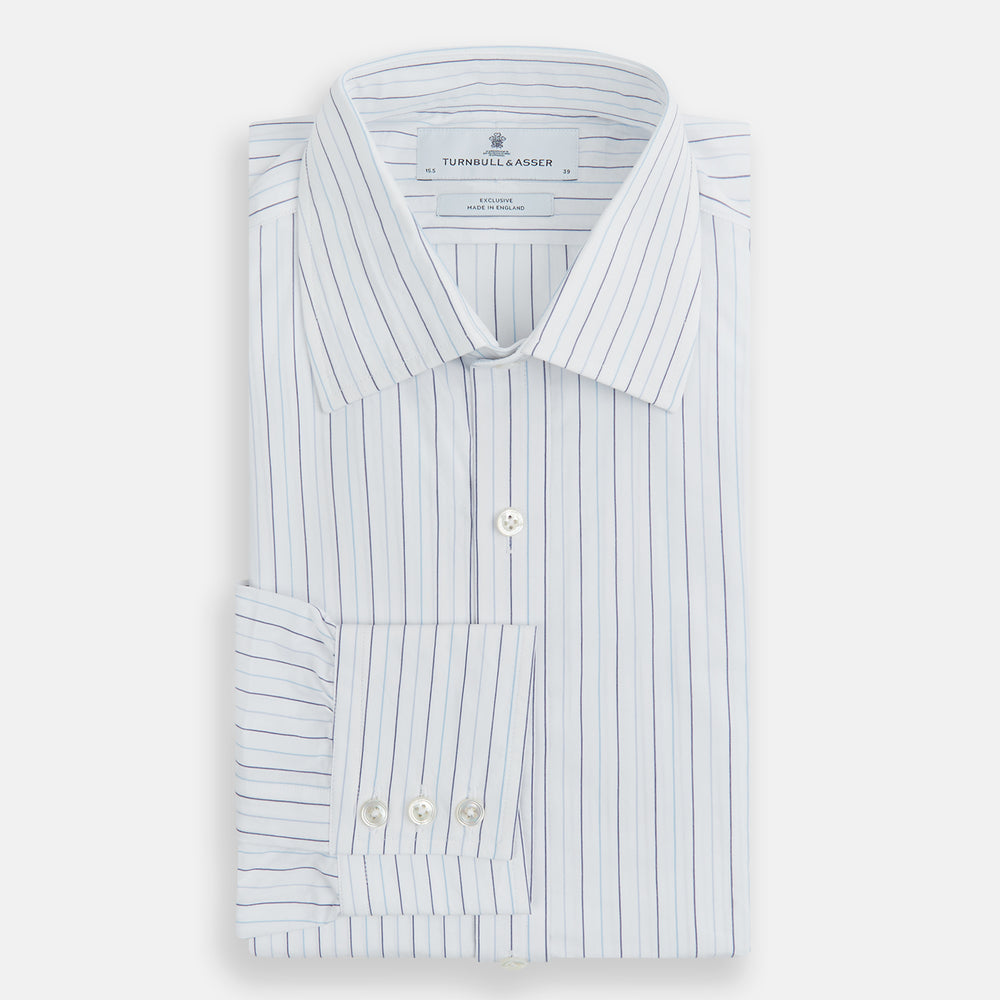 The Turnbull & Asser Blue Wide Pinstripe Mayfair Shirt is a long-sleeved, collared, button-down style crafted from organic cotton, featuring wide blue pinstripes on a white background.