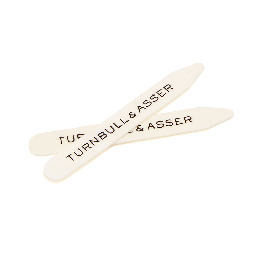 Turnbull & Asser’s Bone Collar Stays in a tan leather, mustard suede-lined tray include six white bone stays—each labeled—offering refined style and perfectly crisp collars.