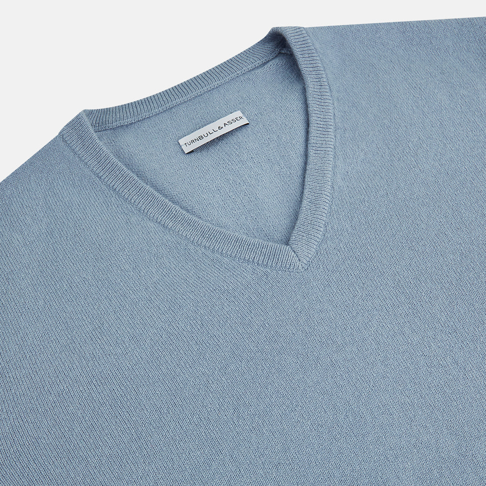 The Turnbull & Asser Frost Blue Cashmere V-Neck Jumper features ribbed cuffs, hem, and neckline. This elegant long sleeve knitwear piece is shown on a plain white background.