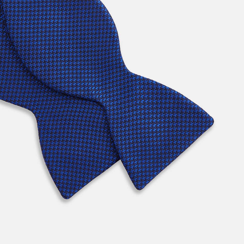 The HOUNDSTOOTH NAVY CRUISE BOW TIE by Turnbull & Asser features a refined textured pattern in blue, neatly tied and set against a white background—a stylish, versatile accessory for the modern gentleman.