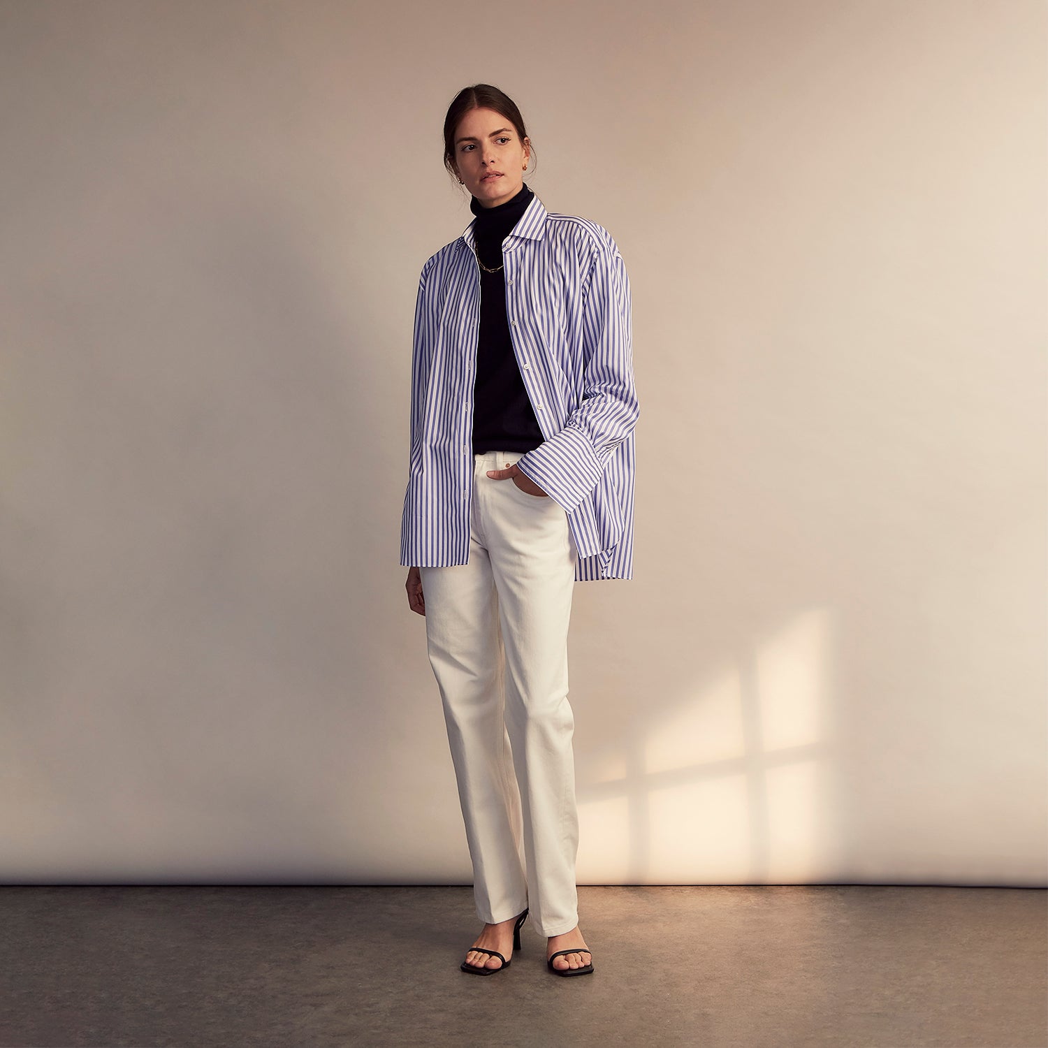 View 11 of product The Turnbull & Asser Pale Blue Candy Stripe Cotton Marlene Shirt is an oversized women's collared shirt with long sleeves, buttoned cuffs, and vertical blue and white stripes, shown laid flat on a white background.