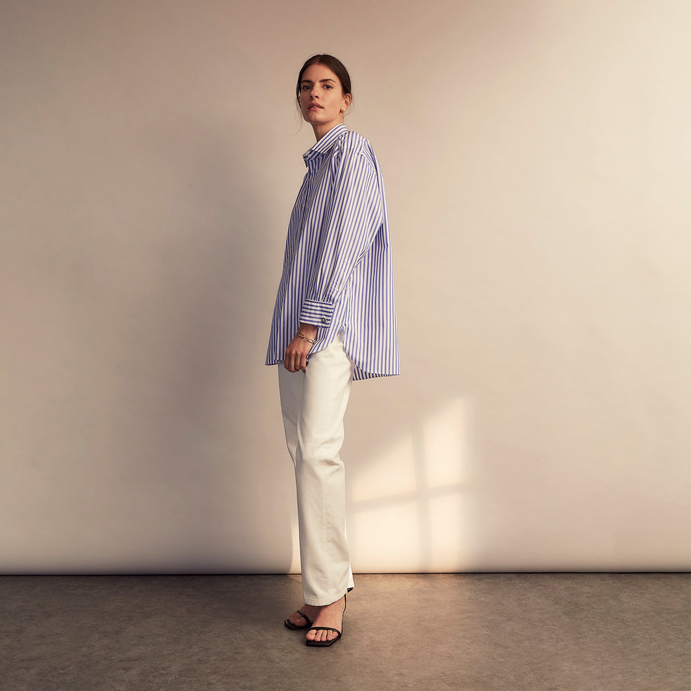 The Turnbull & Asser Pale Blue Candy Stripe Cotton Marlene Shirt is an oversized women's collared shirt with long sleeves, buttoned cuffs, and vertical blue and white stripes, shown laid flat on a white background.