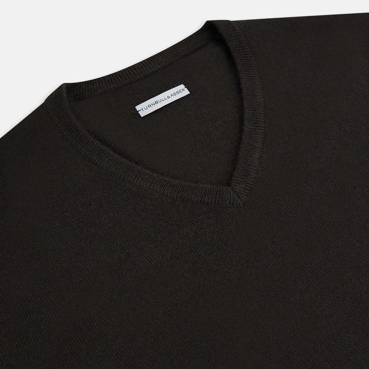 View 2 of product The Turnbull & Asser Dark Brown Cashmere V-Neck Jumper features long sleeves, ribbed cuffs, and a ribbed hem—timeless knitwear shown on a white background, perfect for elevating any wardrobe.