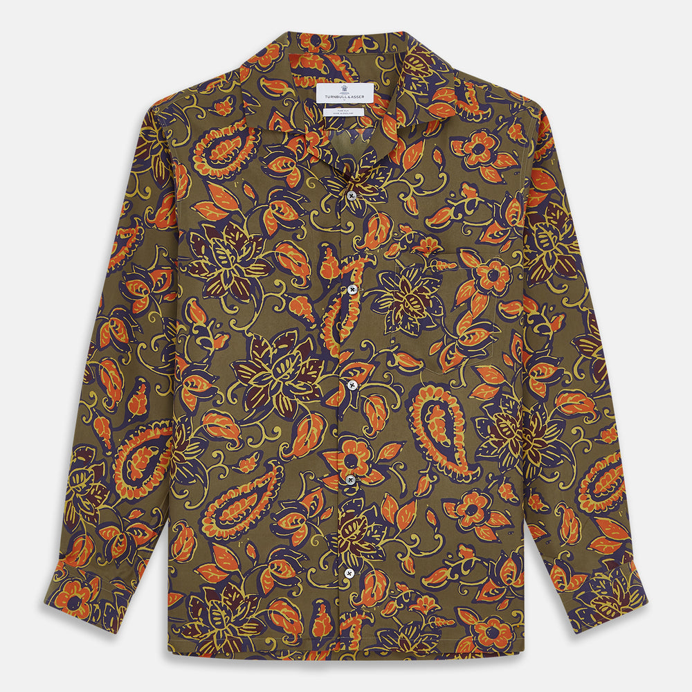 The Turnbull & Asser Khaki Green Floral Silk Holiday Fit Winnington Shirt features a bold floral print with orange, yellow, and purple on an olive background, plus a spread collar and chest pocket for versatile style.