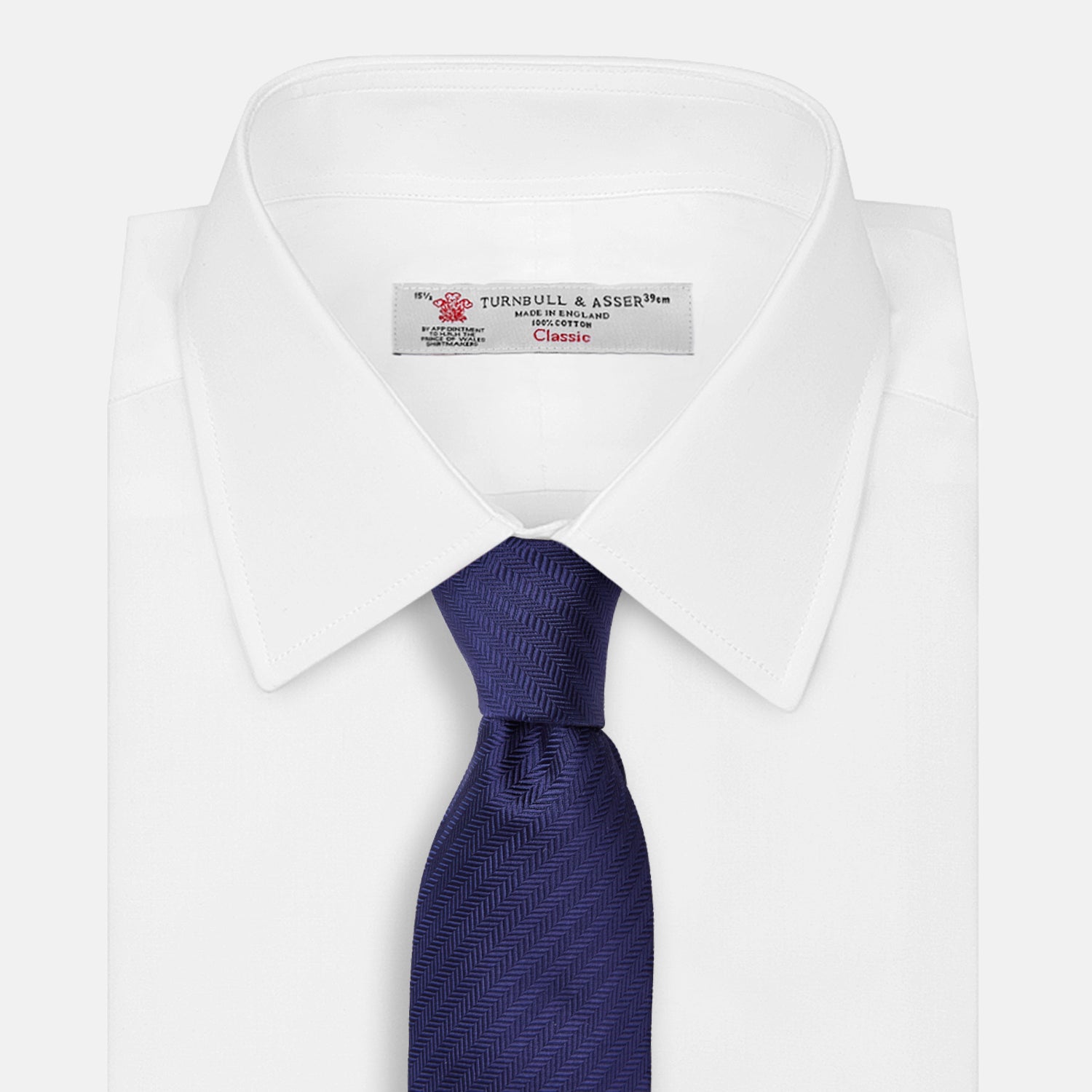 View 4 of product The PLAIN HERRINGBONE NAVY TIE by Turnbull & Asser, crafted from silk with a subtle pattern, is elegantly rolled and displayed against a plain white background.