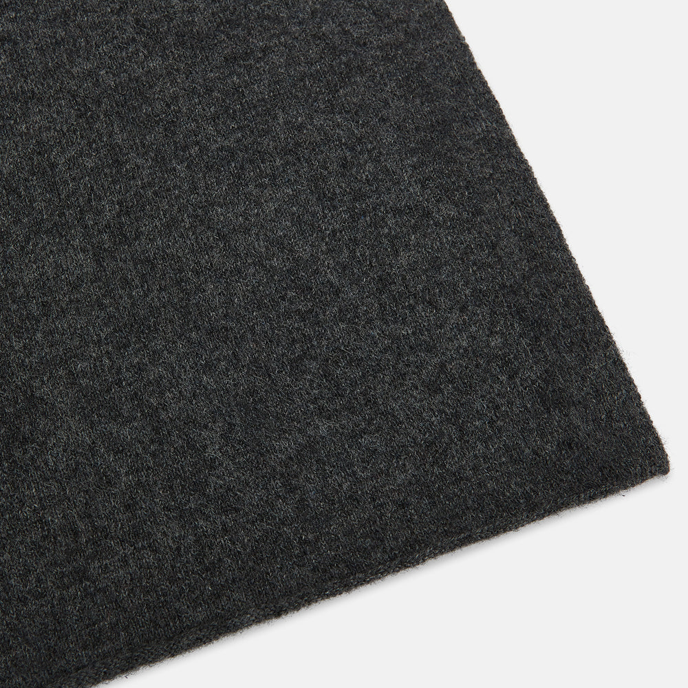 The Turnbull & Asser Plain Graphite Cashmere Knitted Scarf, draped and loosely knotted on a white background, showcases the refined elegance and timeless style of a luxury accessory.