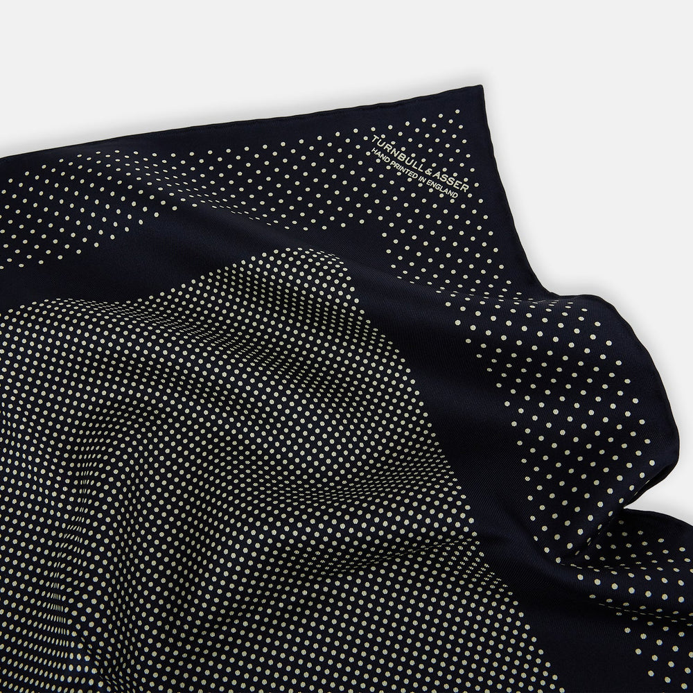 The Turnbull & Asser Navy and Cream Dot Silk Pocket Square features small cream dots, a border design, and displays handmade craftsmanship with one corner folded to show the reverse side.