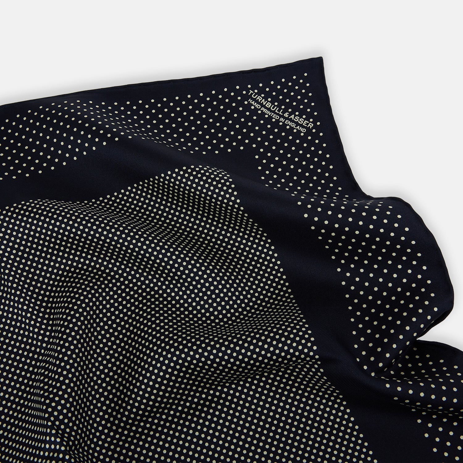 View 2 of product The Turnbull & Asser Navy and Cream Dot Silk Pocket Square features small cream dots, a border design, and displays handmade craftsmanship with one corner folded to show the reverse side.