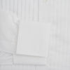View 4 of product The Turnbull & Asser White Pleated Cotton Dress Shirt features a T&A collar, pleated front, double cuffs, and a button-down front, shown laid flat against a white background.