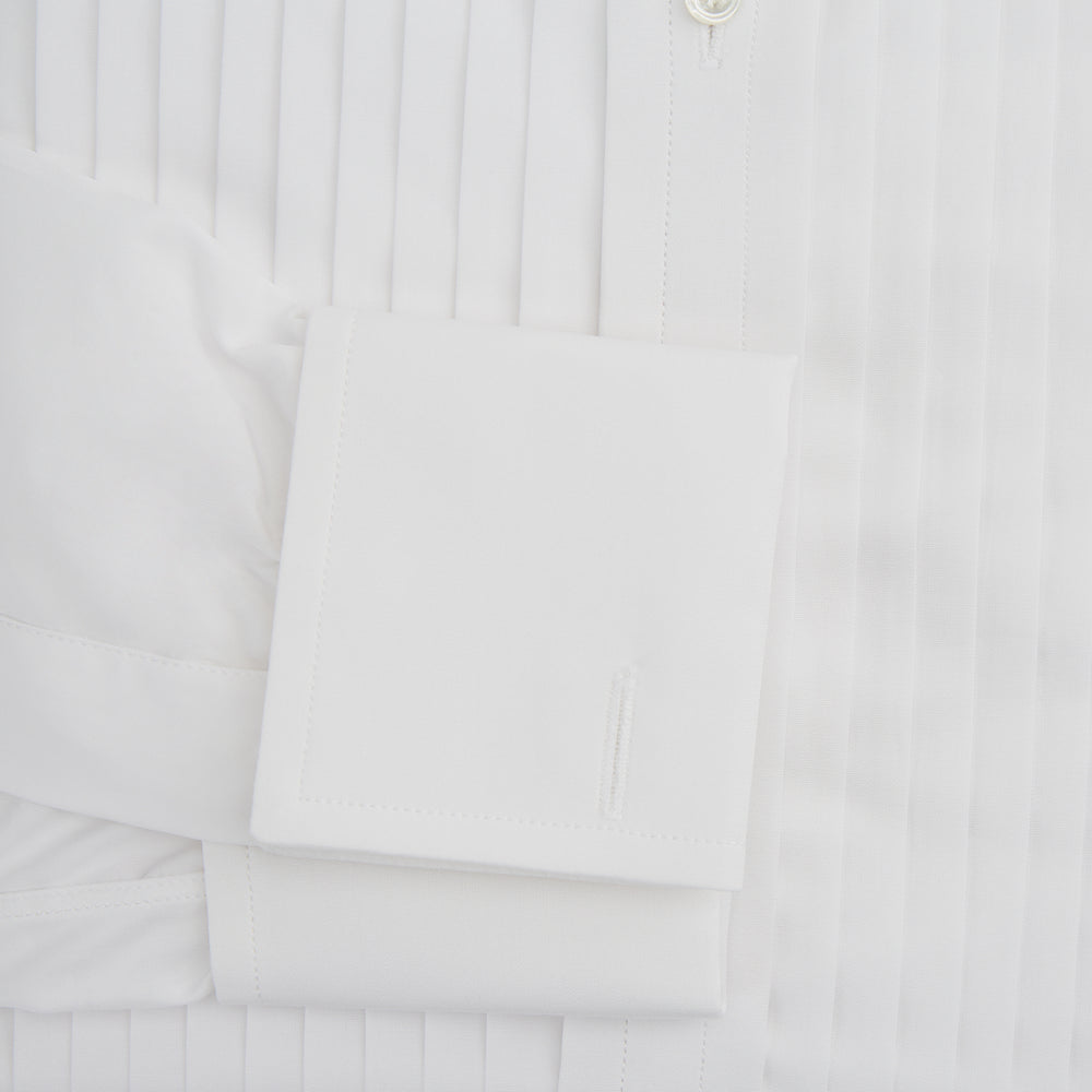 The Turnbull & Asser White Pleated Cotton Dress Shirt features a T&A collar, pleated front, double cuffs, and a button-down front, shown laid flat against a white background.