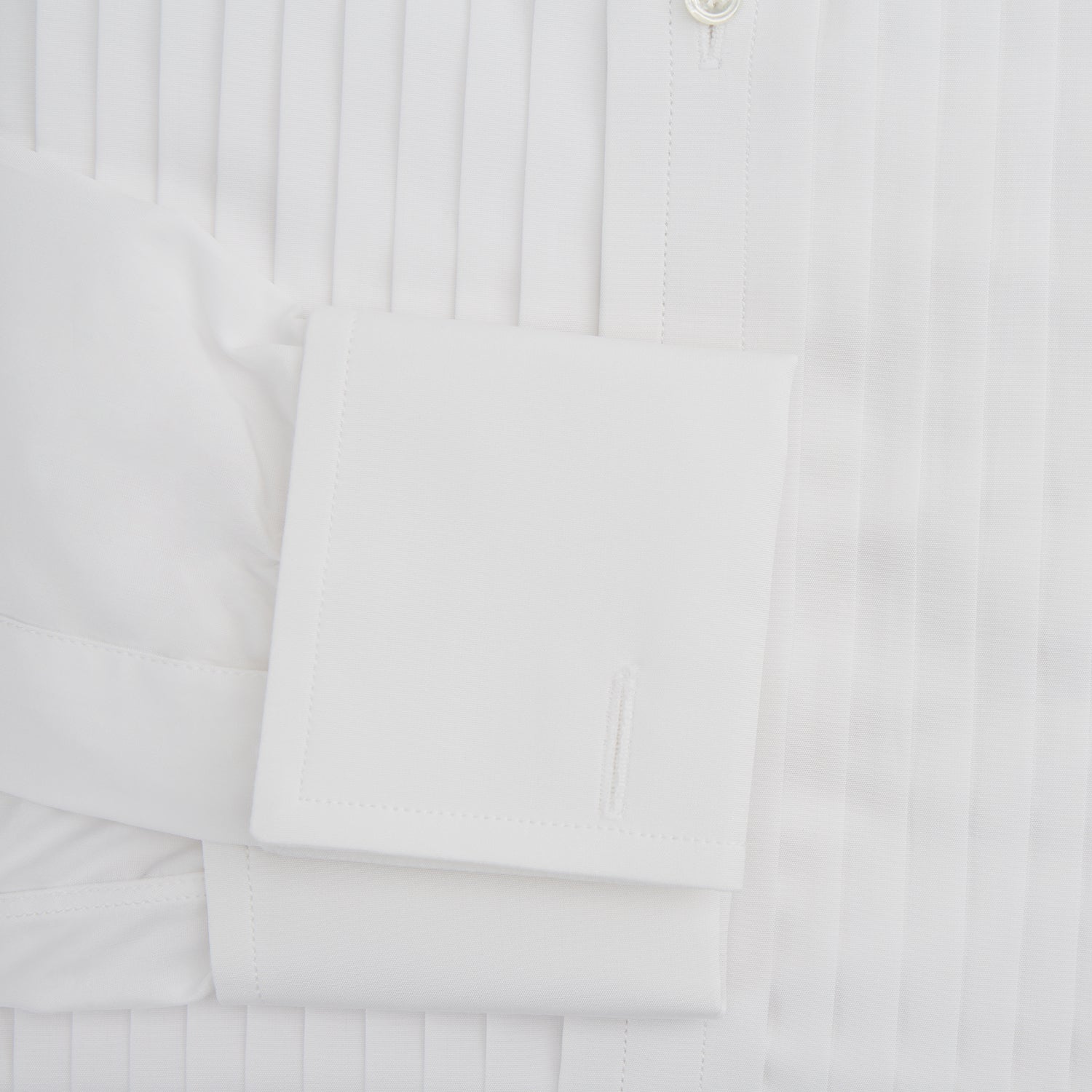 View 4 of product The Turnbull & Asser White Pleated Cotton Dress Shirt features a T&A collar, pleated front, double cuffs, and a button-down front, shown laid flat against a white background.
