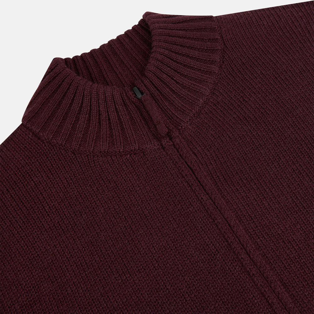 The Turnbull & Asser Burgundy Merino High Neck Zipped Cardigan features long sleeves, a zip-up front, and ribbed collar, cuffs, and hem, crafted from soft merino knitwear and shown on a white background.
